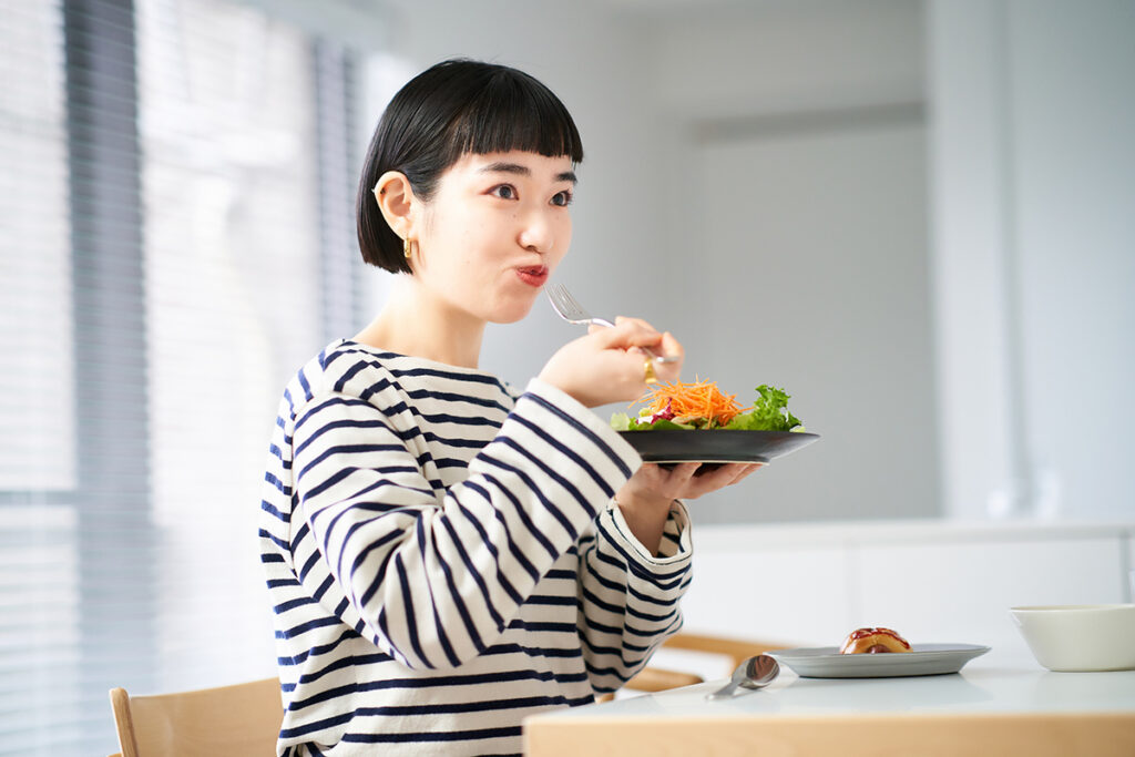 美味しそうにサラダを食べる女性