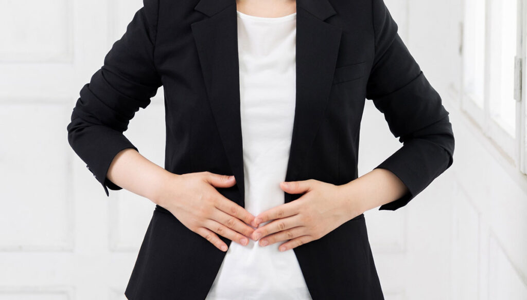 お腹に手を当てる若いビジネスウーマン